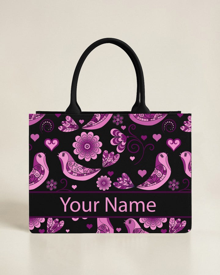 Black structured premium tote bag featuring a pink and purple floral bird pattern with a customizable name section.