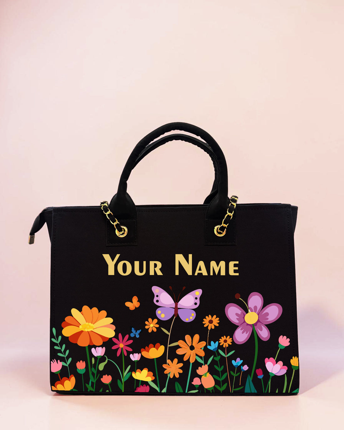 Personalized black tote bag with colorful flowers, butterfly artwork, and custom name print displayed on a pastel background.