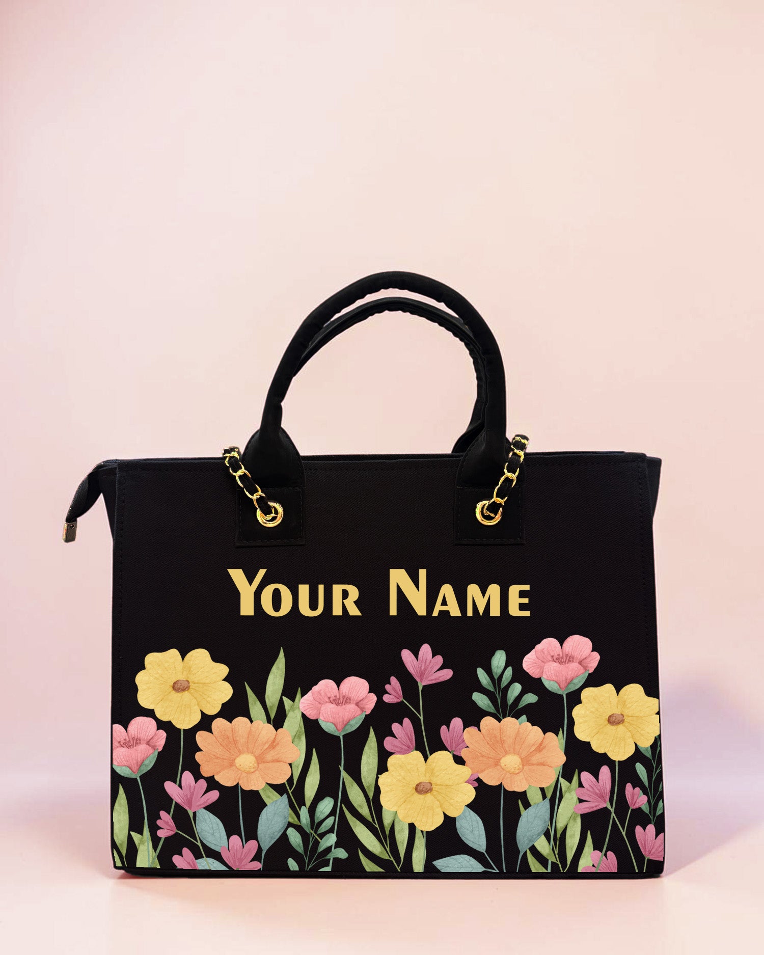 Personalized black floral tote bag with pastel flower artwork and custom name print displayed on a soft pastel background.